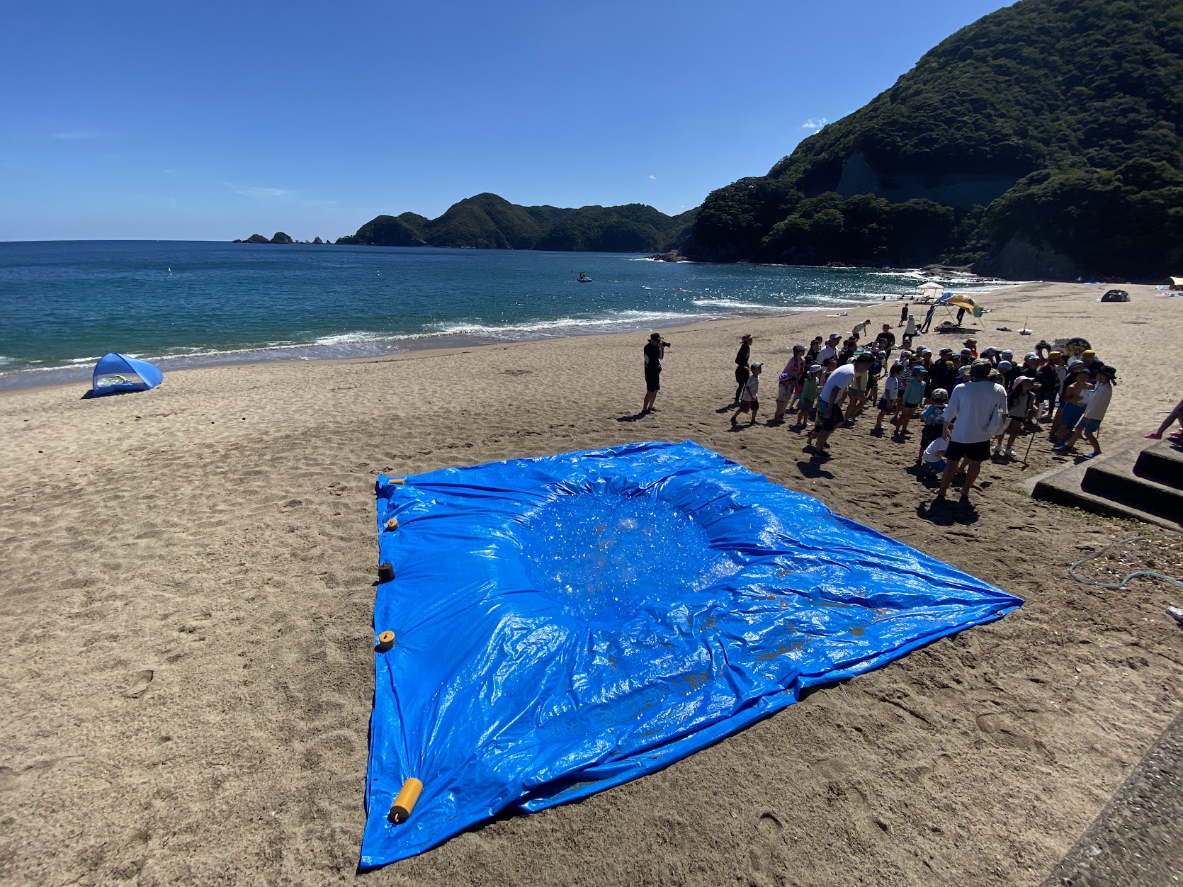 ブルーシートの上に氷水。横には参加者の子供たち